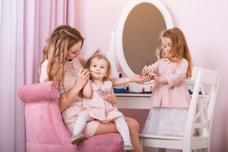 Mother and two daughters doing lip make-up.の写真素材