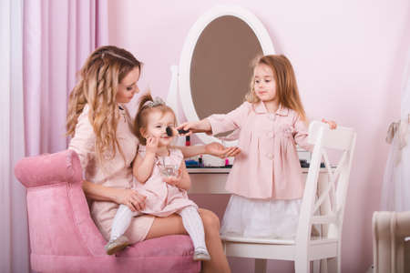 Mother and two daughters doing lip make-up.の写真素材