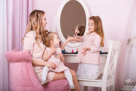 Mother and two daughters doing lip make-up.の写真素材