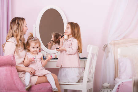 Mother and two daughters doing lip make-up.の写真素材