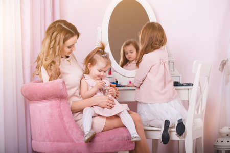 Mother and two daughters doing lip make-up.の写真素材
