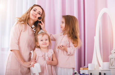 Mother and two daughters doing lip make-up.の写真素材