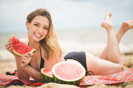 Beautiful girl with watermelon near the seaの写真素材
