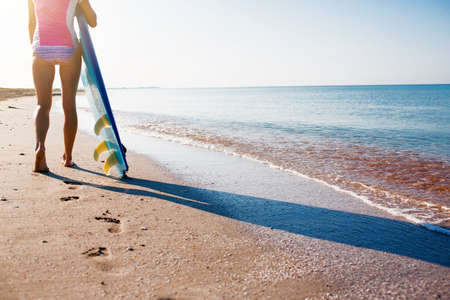 Surfer girl on the beach waiting for waves