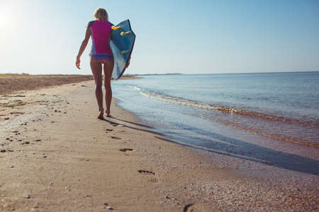 Surfer girl on the beach waiting for waves