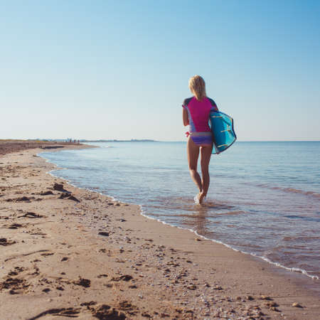 Surfer girl on the beach waiting for waves