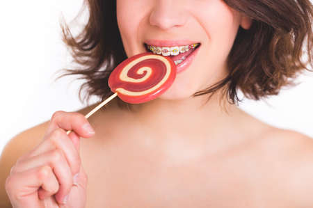 Close-up shot of girl with multicolored bracket systems and lollipopの写真素材
