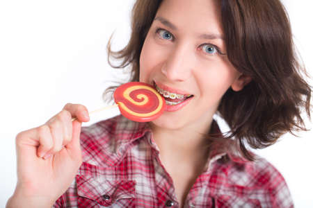 Close-up shot of girl with multicolored bracket systems and lollipop