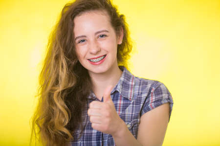 Young girl in a plaid shirt showing her dental bracesの写真素材