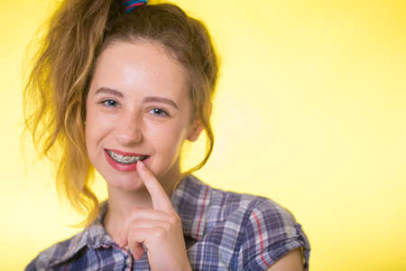 Young girl in a plaid shirt showing her dental braces