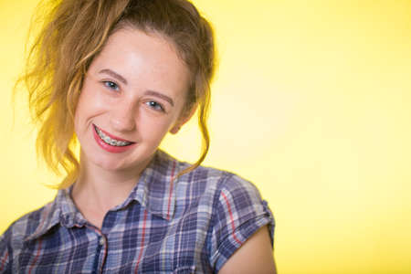 Young girl in a plaid shirt showing her dental bracesの写真素材