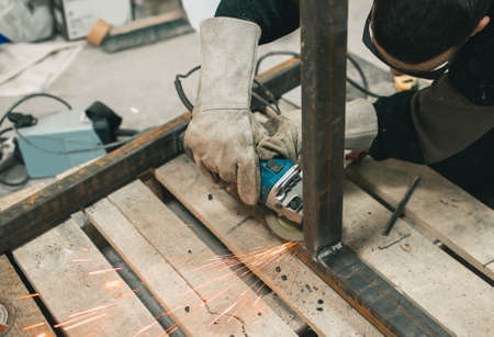 Worker in protective glasses performs electric polishing of partsの写真素材