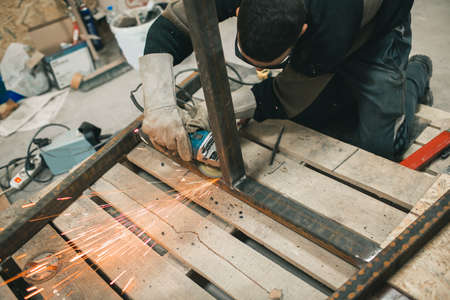 Man doing electroshooting of parts on the steel structure in the factory