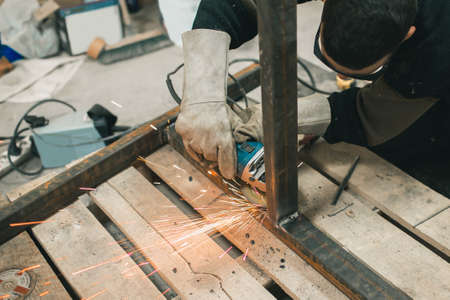 Worker in protective glasses performs electric polishing of partsの写真素材