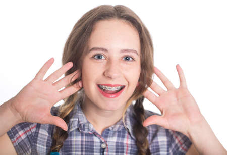 A cute piggy girl in a checkered shirt shows her braces. Isolated on white. Dental concept