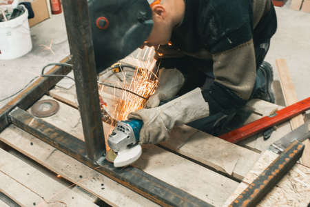 Man doing electroshooting of parts on the steel structure in the factory