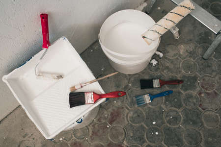 Buckets with paint and brushes stand near the wall. Accessories for repair. up viewの写真素材