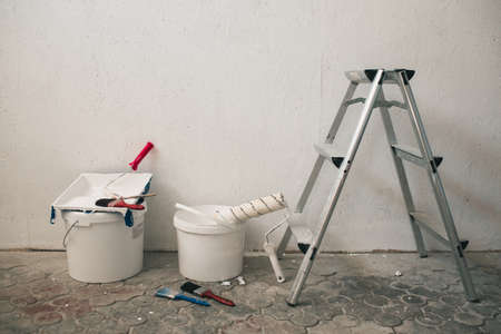 Buckets with paint and brushes stand near the wall. Accessories for repairの写真素材