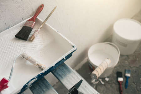 Buckets with paint and brushes stand near the wall. Accessories for repair