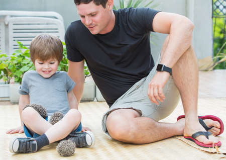 Young man with son playing with hedgehog baby