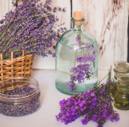 Lavender oil with fresh flowers on wooden background.