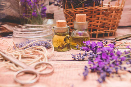 Lavender oil with fresh flowers on wooden background.