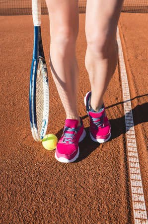 Closeup photo of female legs with tennis racketの写真素材