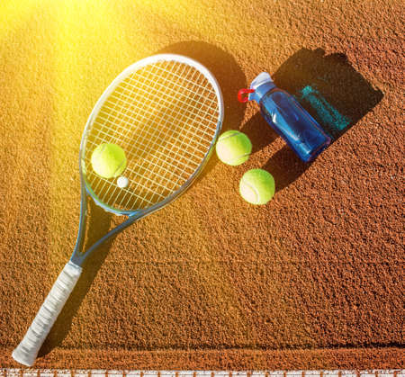Tennis equipment and bottle of water on the clay courtの写真素材