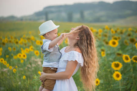 Mother with baby son in sunflower fieldの写真素材