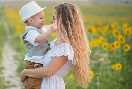 Mother with baby son in sunflower fieldの写真素材