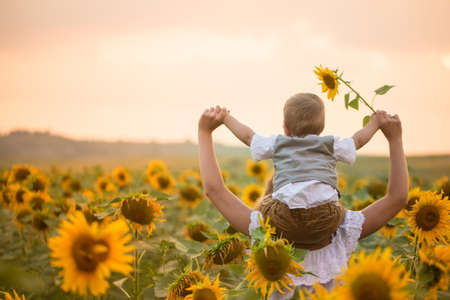 Mother with baby son in sunflower fieldの写真素材