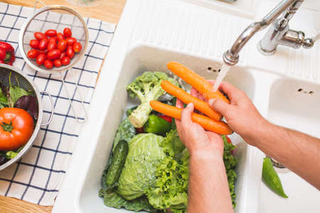 Man washes vegetables before eatingの写真素材