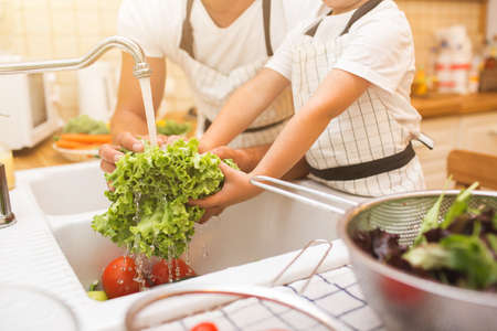 Father with son washes vegetables before eatingの写真素材