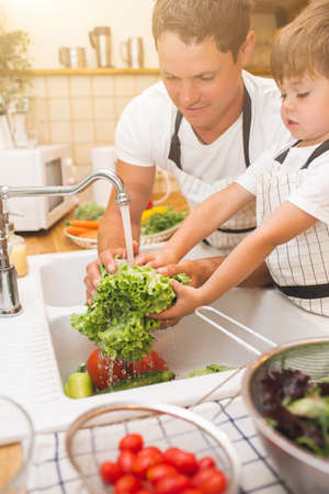 Father with son washes vegetables before eatingの写真素材