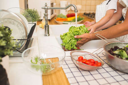 Father with son washes vegetables before eatingの写真素材