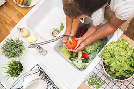 Father with son washes vegetables before eatingの写真素材