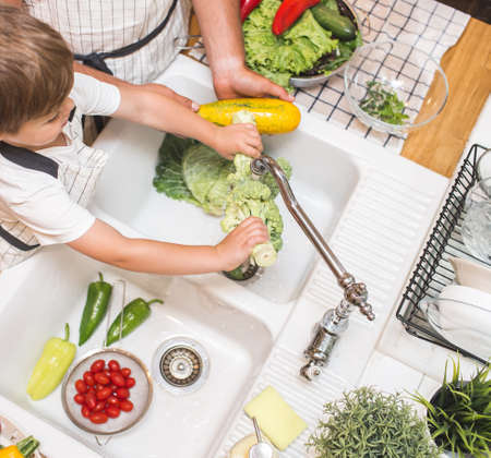 Father with son washes vegetables before eatingの写真素材
