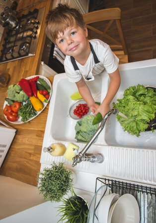 Little boy washes vegetables before eatingの写真素材
