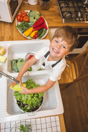 Little boy washes vegetables before eatingの写真素材