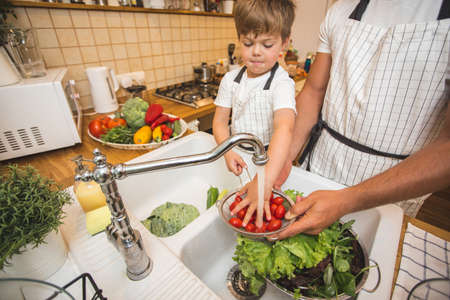 Father with son washes vegetables before eatingの写真素材