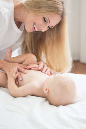 Portrait of young beautiful mother making massage to baby sonの写真素材