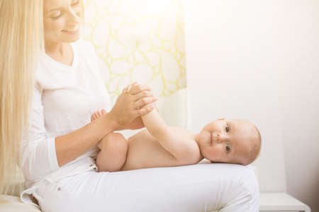Portrait of young beautiful mother making massage to baby sonの写真素材