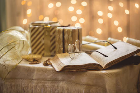 Holy bible book with eyeglasses. Christmas lights on background.の写真素材