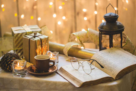 Old book with eyeglasses. Christmas decoration on background. Cup of coffeeの写真素材