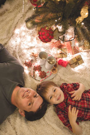 Father and son laying under christmas tree.の写真素材
