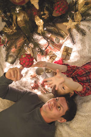 Father and son laying under christmas tree.の写真素材