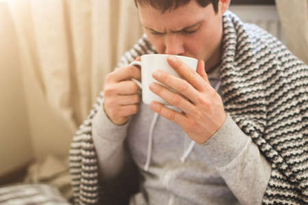 Young man laying in bad with laptop and cup of tea.の写真素材