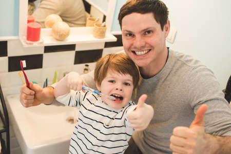 Young father with his son brushing teeth