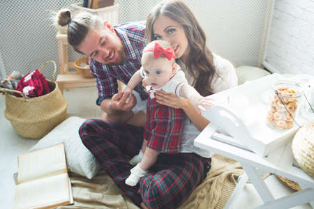 Happy young family mother, father and daughter playing on carpet at home.の写真素材