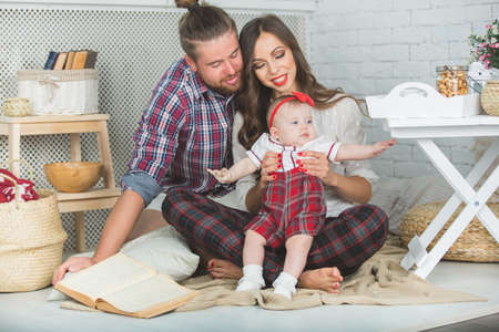 Happy young family mother, father and daughter playing on carpet at home.の写真素材